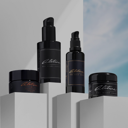 photo of Alitura Gold Serum, Night Cream, Pearl Cleanser, and Meteorite Scrub on white pedestals with white and blue sky background