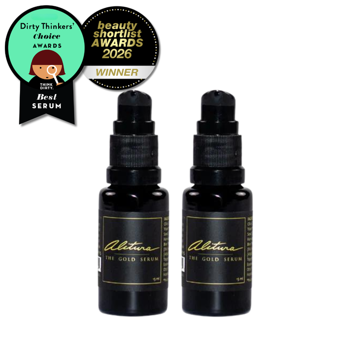 Two black serum bottles with gold labels on a white background, featuring awards badges.