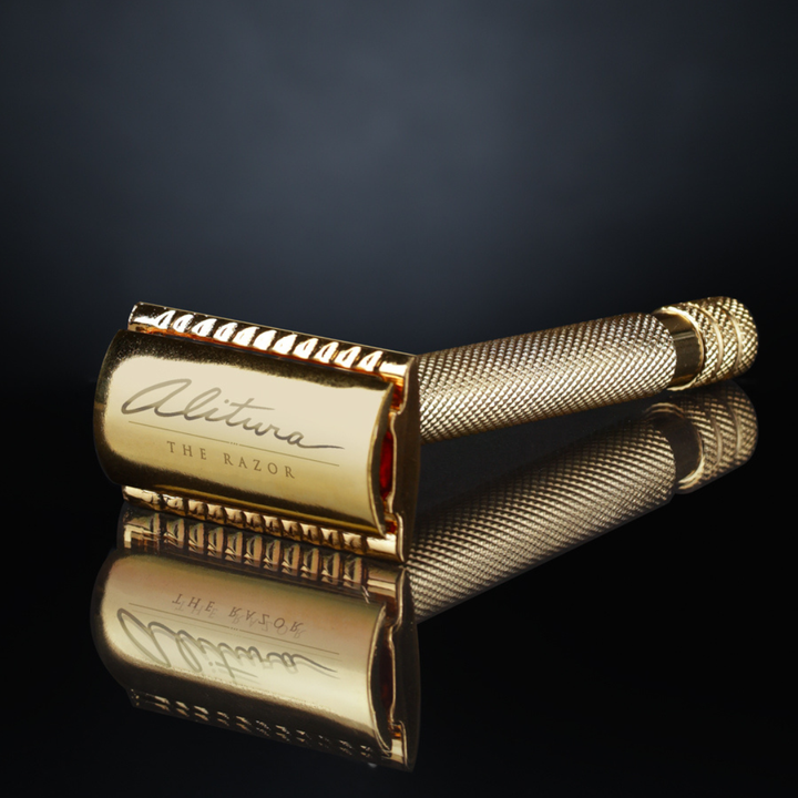 Gold safety razor with 'Alitura' branding on a reflective surface against a dark background