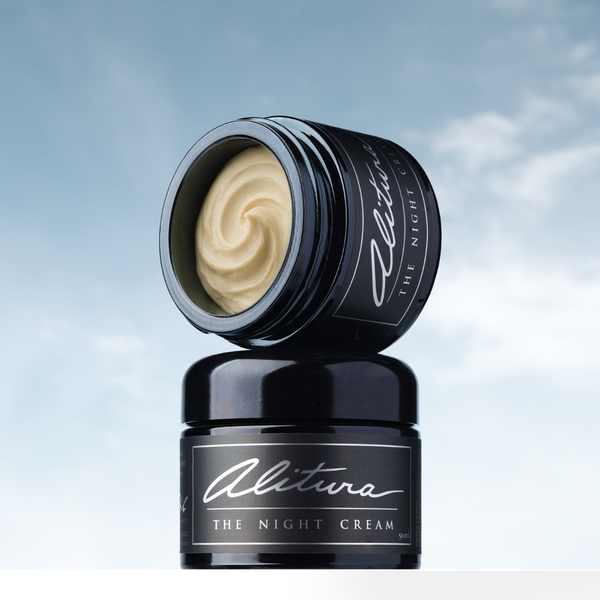 Black jar of 'The Night Cream' by Alitura with a swirl of cream on a light blue background